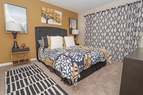 A bedroom with a patterned bedspread and a black and white rug at Magnolia apartments in Shreveport, LA